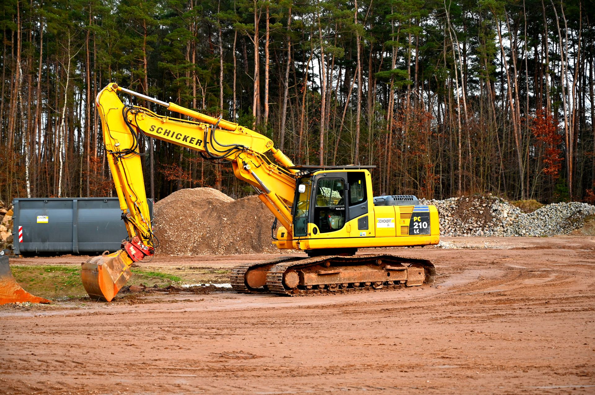 Excavator working on a cleared site at the treeline